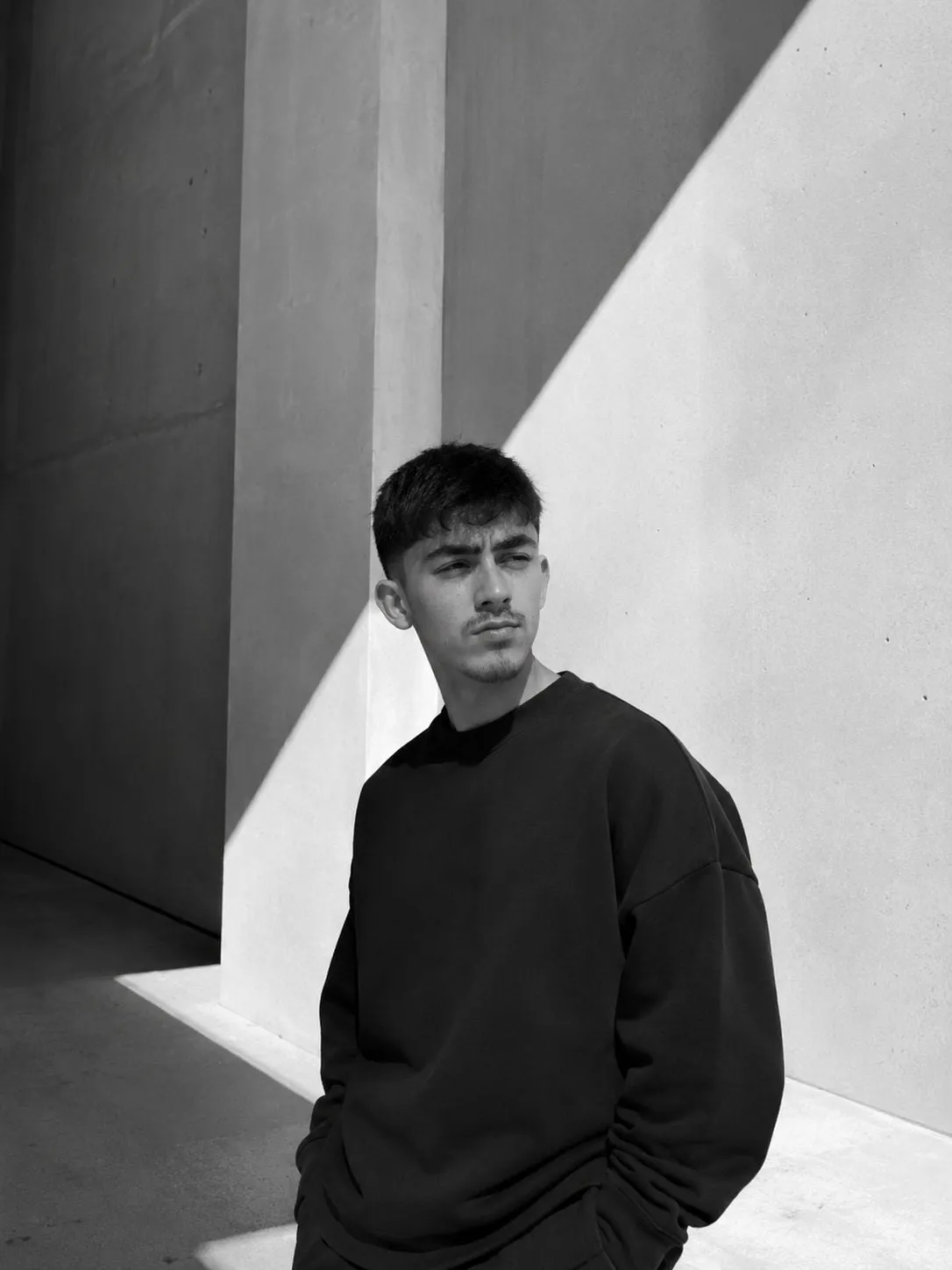 Duha Ege, black and white portrait in front of a concrete wall